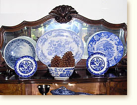 Display of antique blue and white transferware on an antique French mirrored back buffet.
